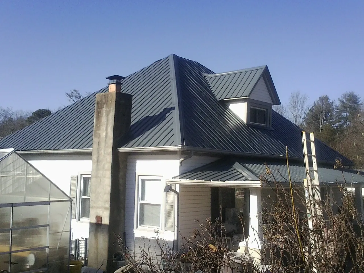 Dark blue standing seam metal roof on a white farmhouse with dormer — Slate & Tile Roof Repair by Roofing Brothers in Kechi