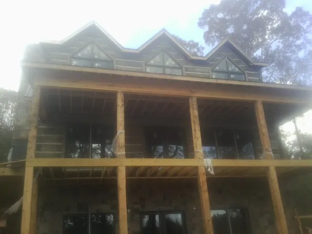 Dormers and porch framing on a large log home under construction — Roof Coating work by our crew in Kechi