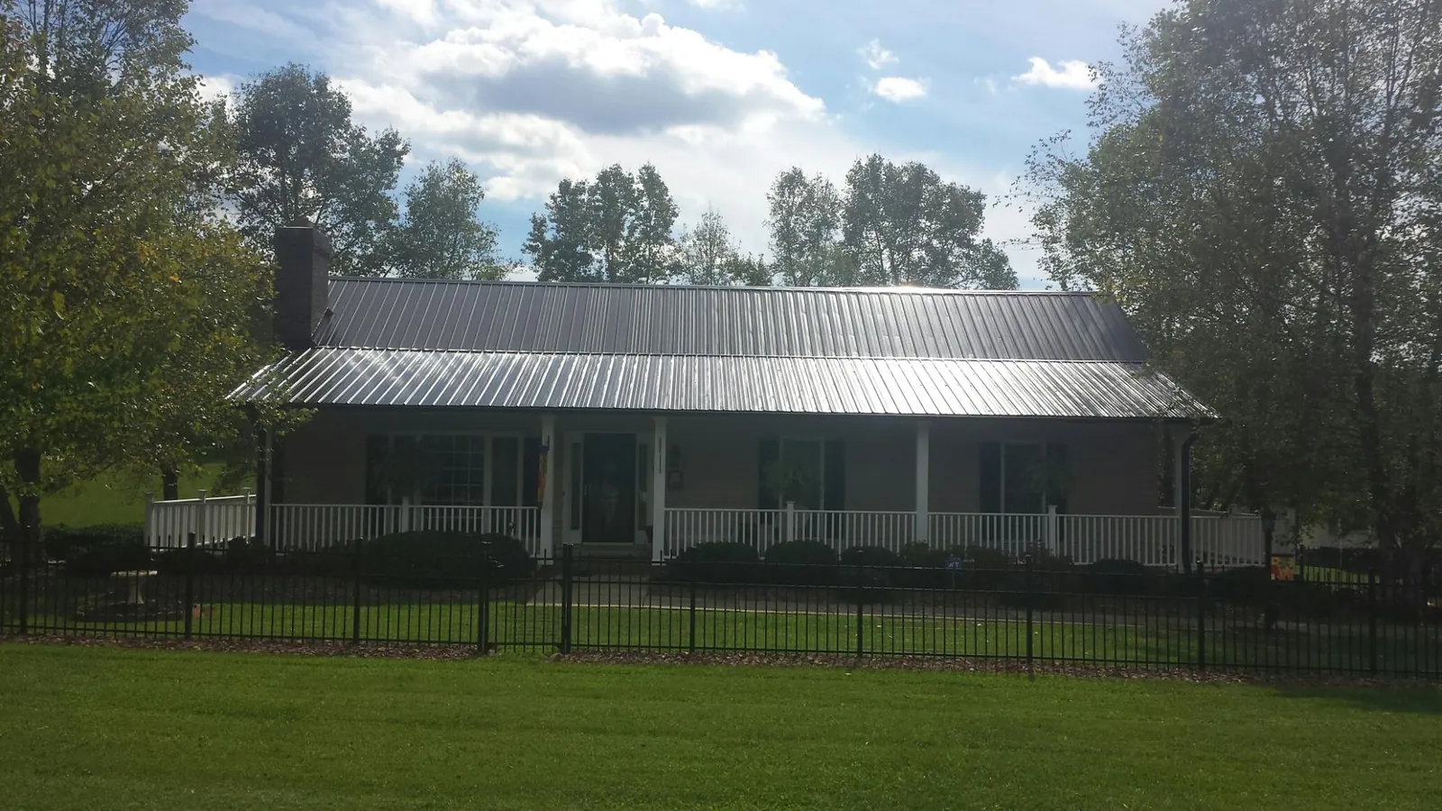 Gray metal roof on a brick ranch with a full width front porch — Gutter Guard Installation work by our crew in Kechi