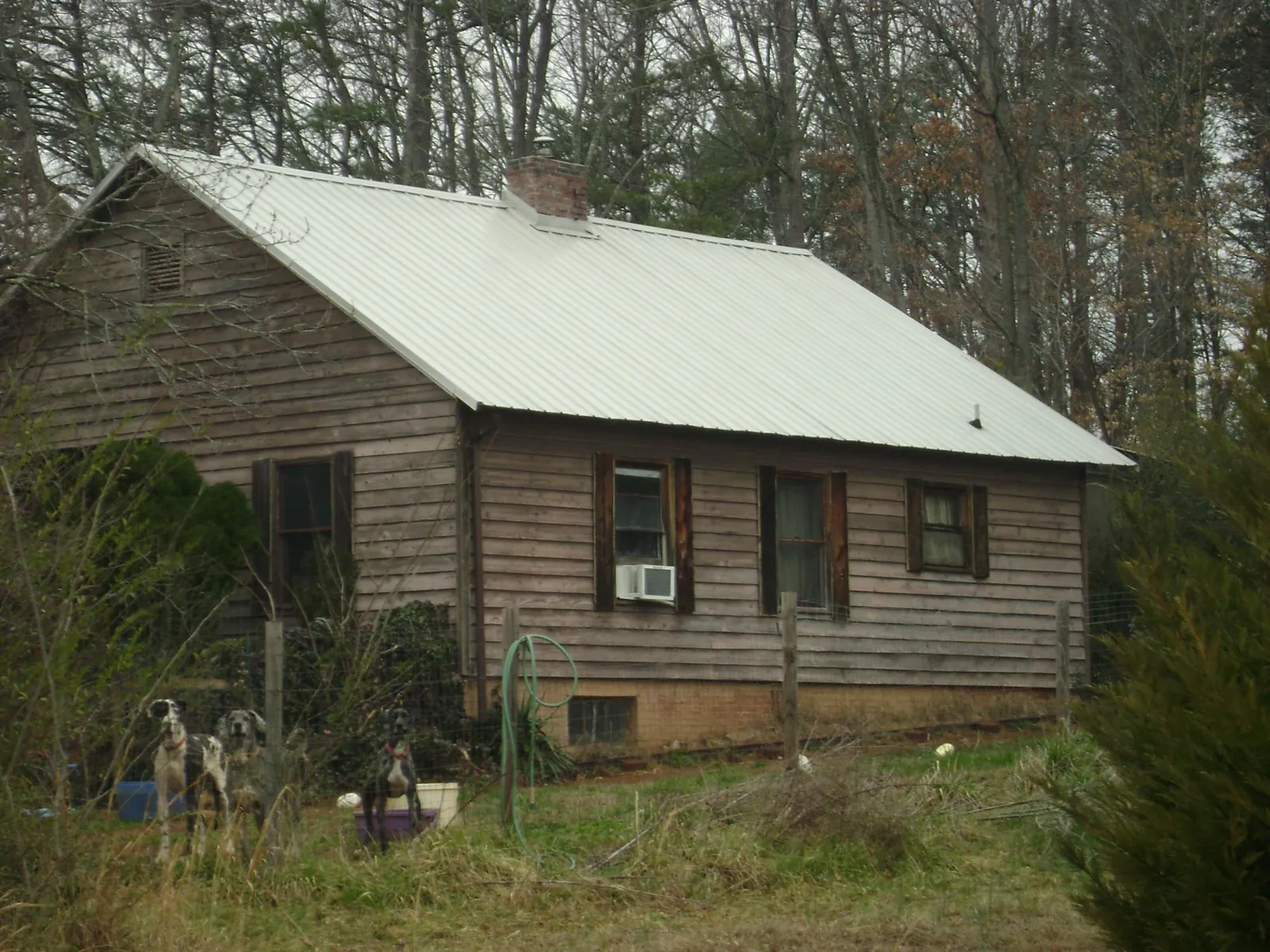 White metal roof on an old wood sided farmhouse, from a Metal Roof Installation job in Kechi