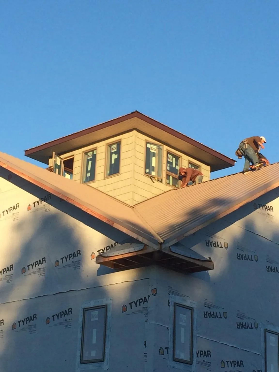Roofers working around a rooftop cupola on a new metal roof at sunset — Roof Waterproofing in Kechi by Roofing Brothers